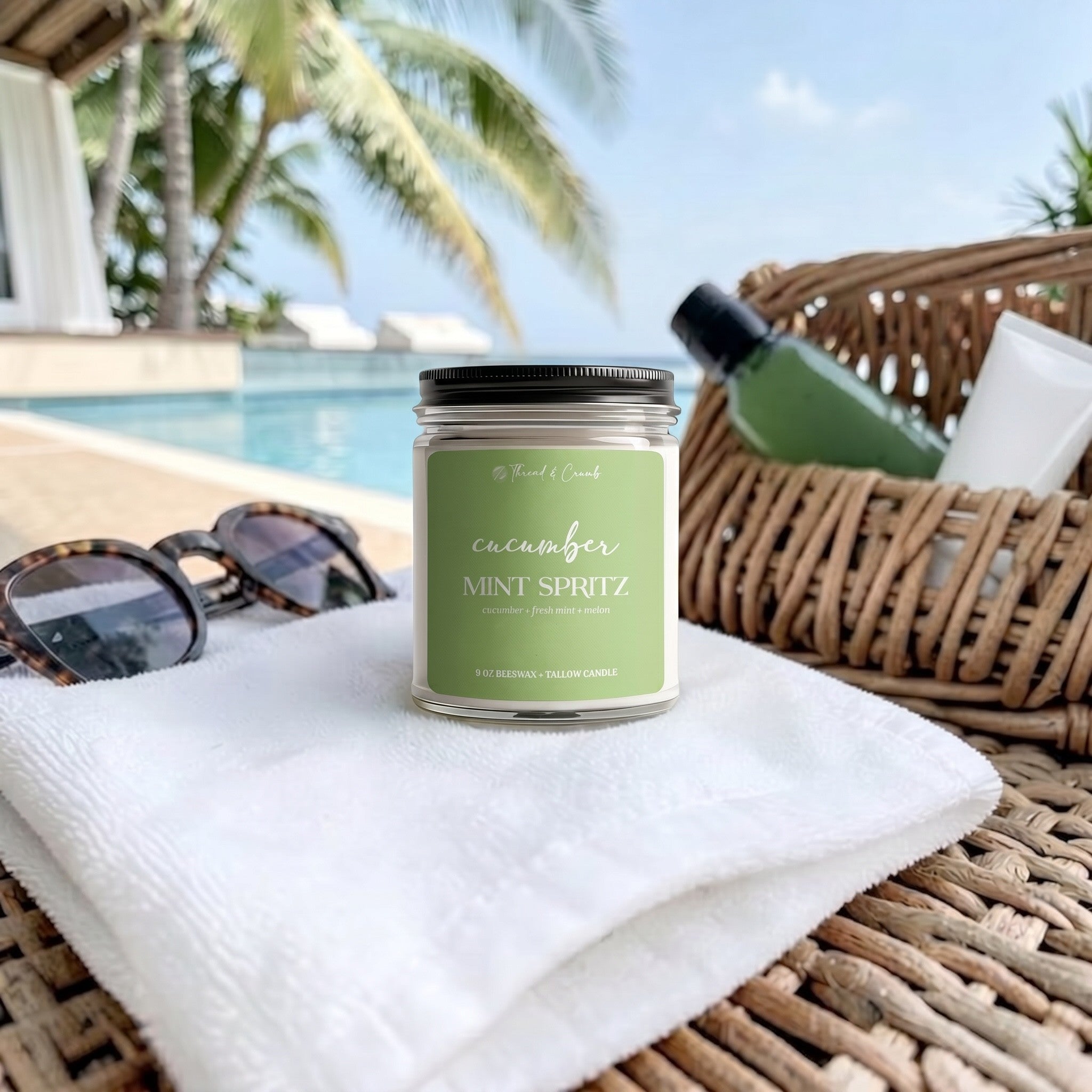 Handmade Cucumber Mint Spritz beeswax and tallow candle displayed poolside on a white towel beside sunglasses.