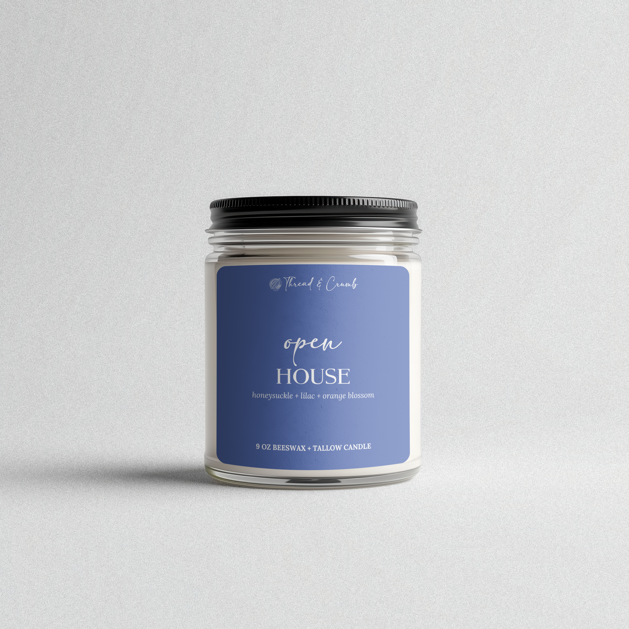 Front view of the handmade Open House beeswax and tallow candle in a clear glass jar.