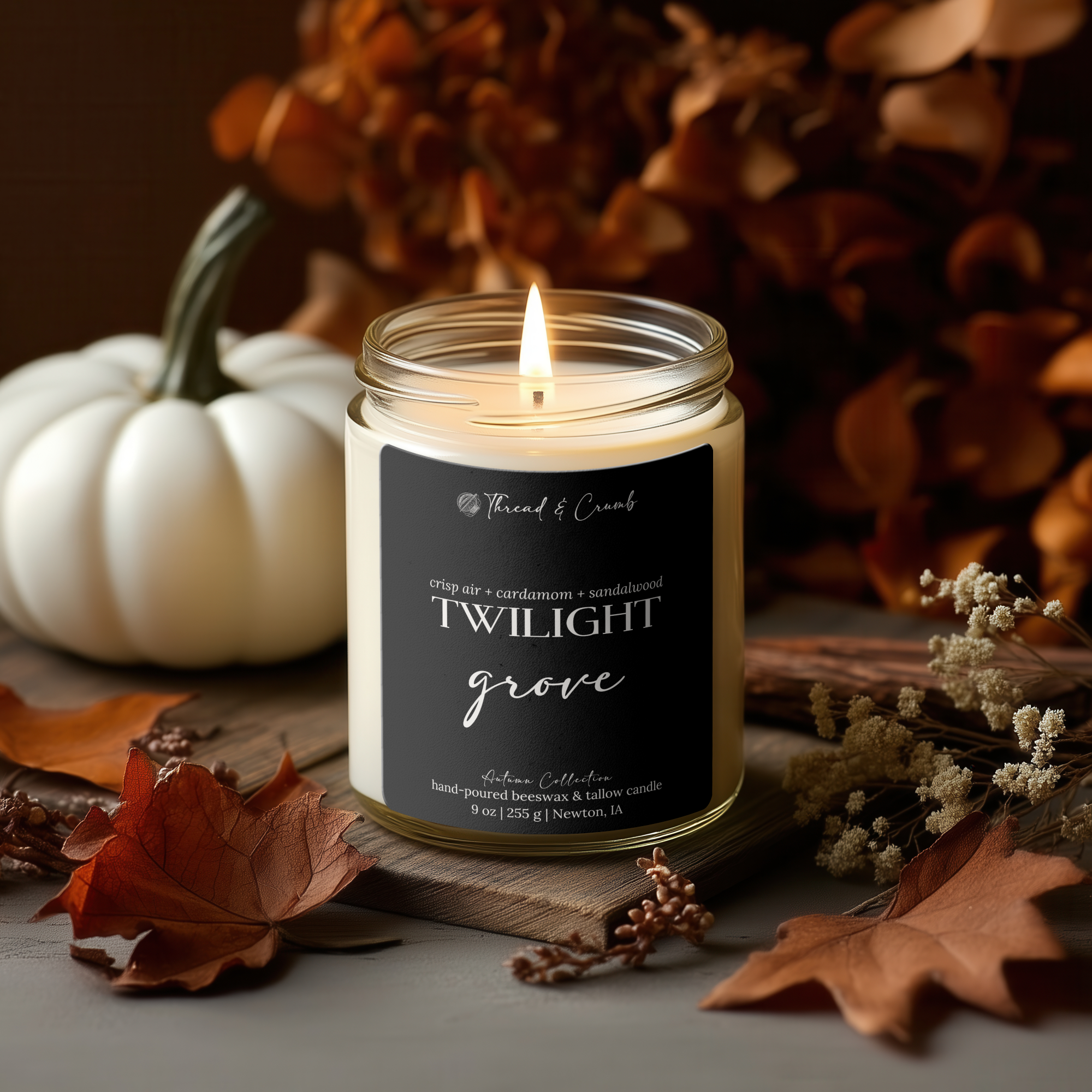 Handmade Twilight Grove beeswax and tallow candle surrounded by autumn leaves and seasonal décor.
