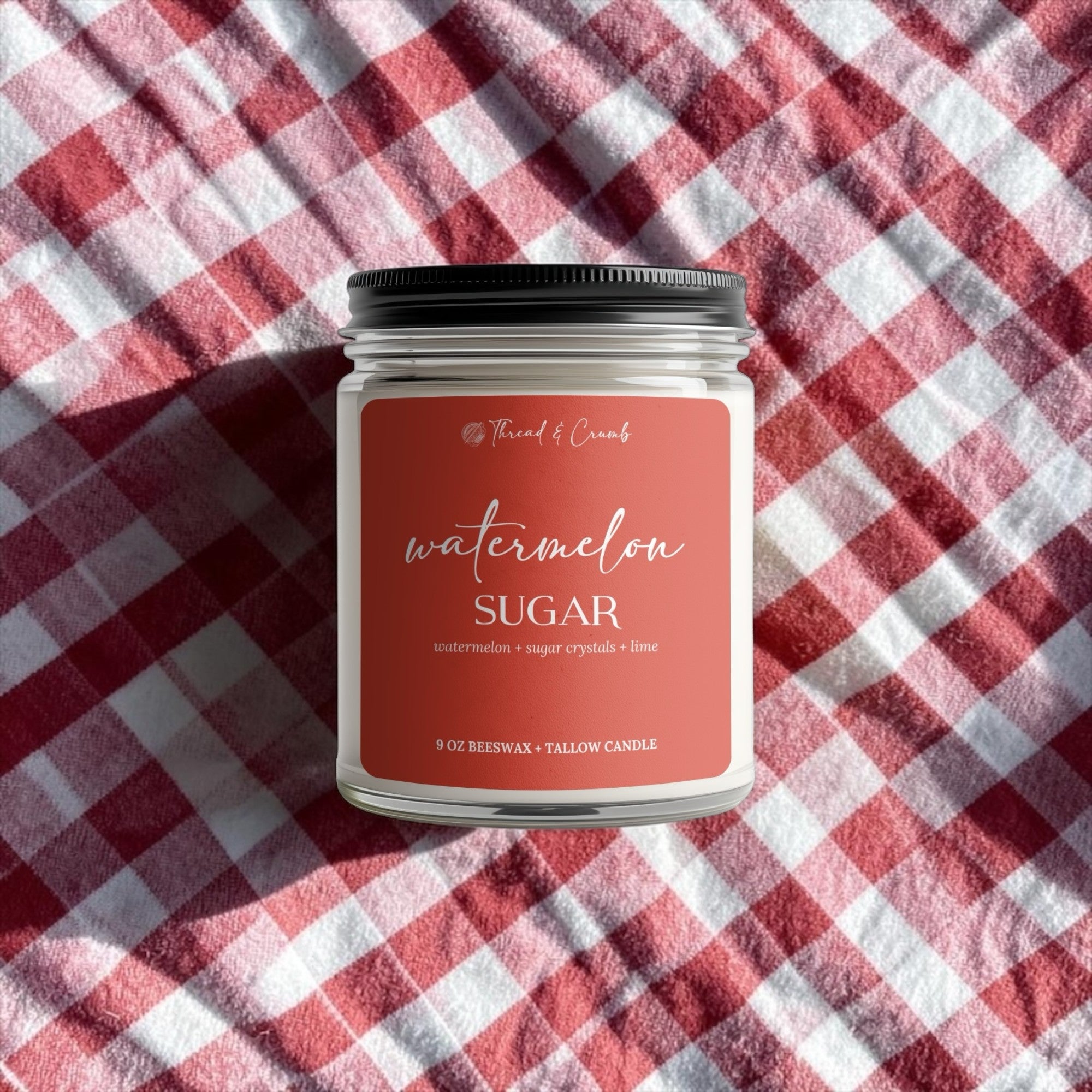 Handmade Watermelon Sugar beeswax and tallow candle on a red and white picnic blanket.